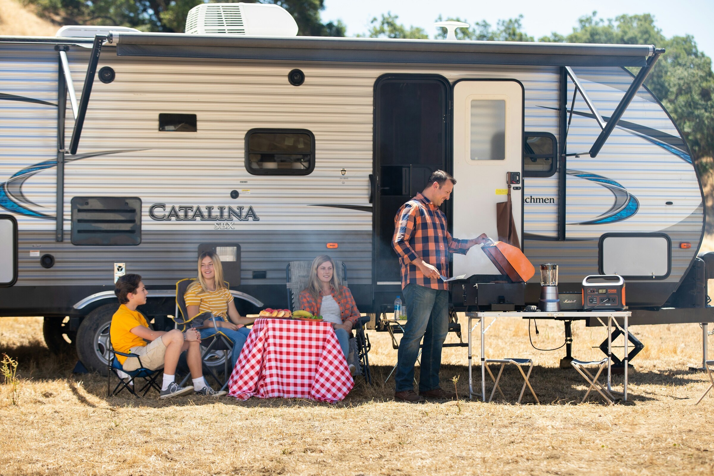 Family and friends grilling outside of an RV